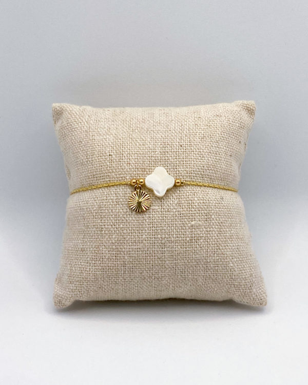 Bracelet composé d'une pierre de nacre blanche naturelle, d'une chaîne plaqué or et d'un petit pendentif soleil, élégant et fin.