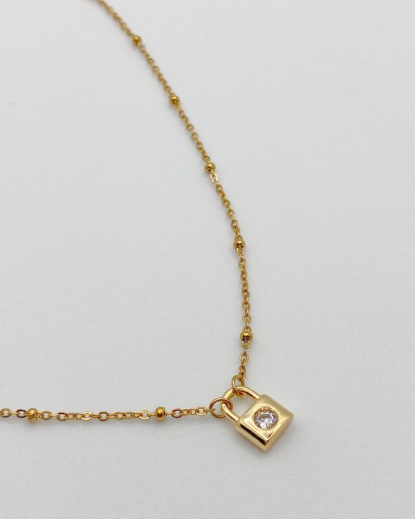 Collier court et élégant composé d'une chaîne en acier inoxydable et billes et d'un petit cadenas avec strass Swarovski. Ne noircit pas.