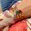 Bracelet en acier inoxydable avec une chaîne doré et des pierres semi-précieuses silimanite couleur rubis, silimanite couleur émeraude, pierre de lune et d'une perle de culture