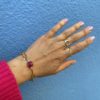 Bracelet en acier inoxydable avec une chaîne doré et des pierres semi-précieuses silimanite couleur rubis, silimanite couleur émeraude, pierre de lune et d'une perle de culture