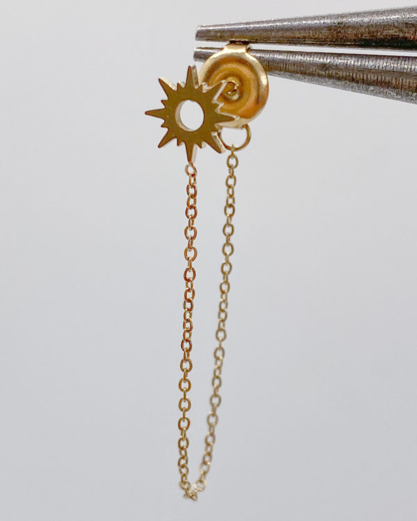 Boucles d'oreilles composées d'une puce en forme de soleil et d'une chaîne pendante reliée au poussoir. A porter seules ou en accumulation.
